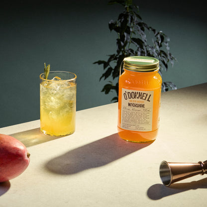 Auf der rechten Seite ein Glas Golden Mango Likör und auf der linken Seite ein Glas mit Eis und Mango Likör.