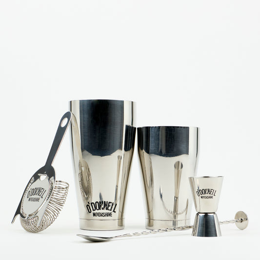O'Donnell Moonshine Bar-Set aus Edelstahl mit Boston Shaker, Barsieb, Jigger und Barlöffel vor weißem Hintergrund.