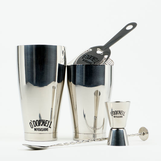 O'Donnell Moonshine Bar-Set aus Edelstahl mit Boston Shaker, Barsieb, Jigger und Barlöffel vor weißem Hintergrund.