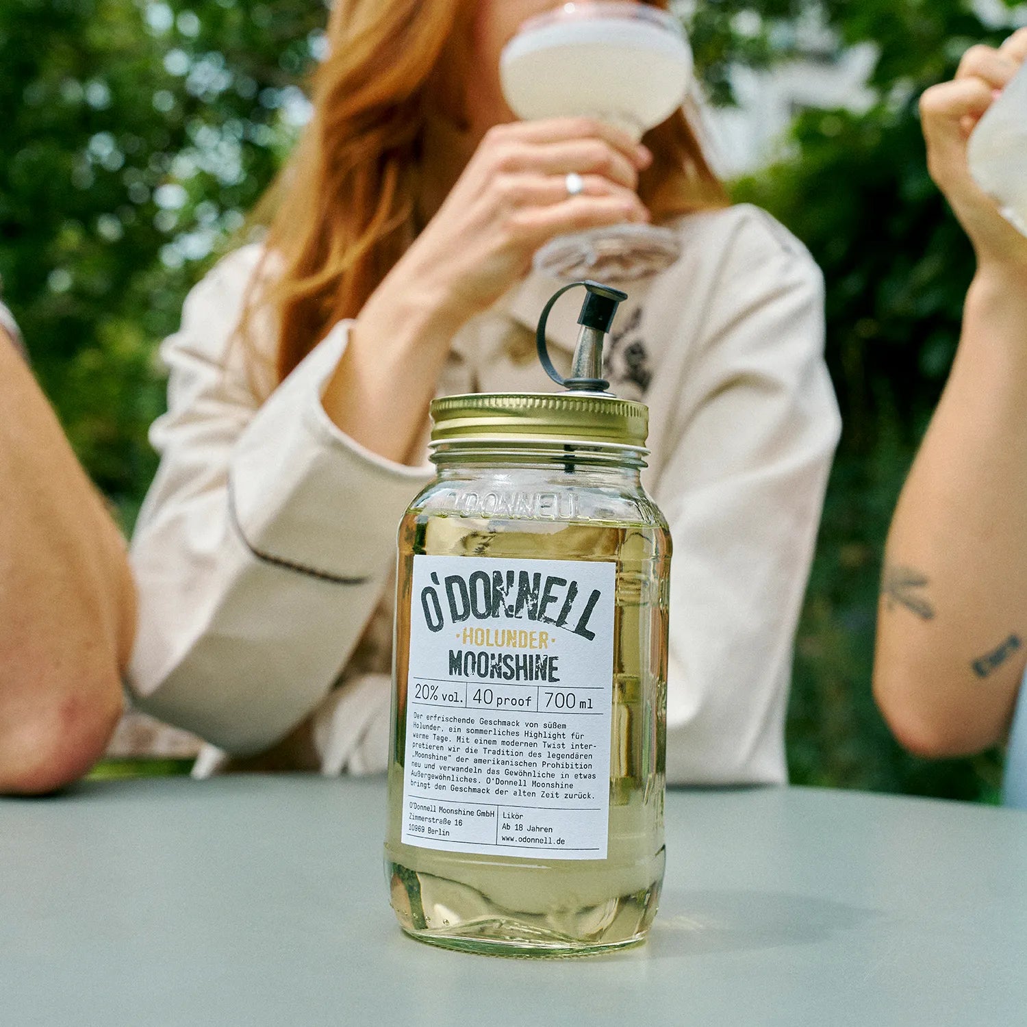O'Donnell Moonshine Holunder-Likör mit einem Mason Jar vor einer Gruppe die ihn als Cocktail genießt.
